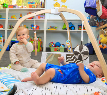 Infants playing under the activity gym