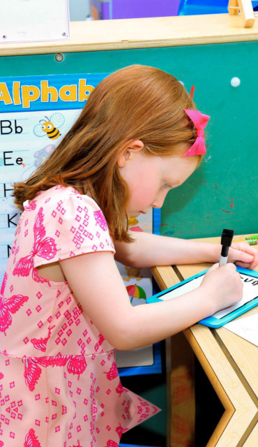 Preschooler practicing writing at the alphabet board