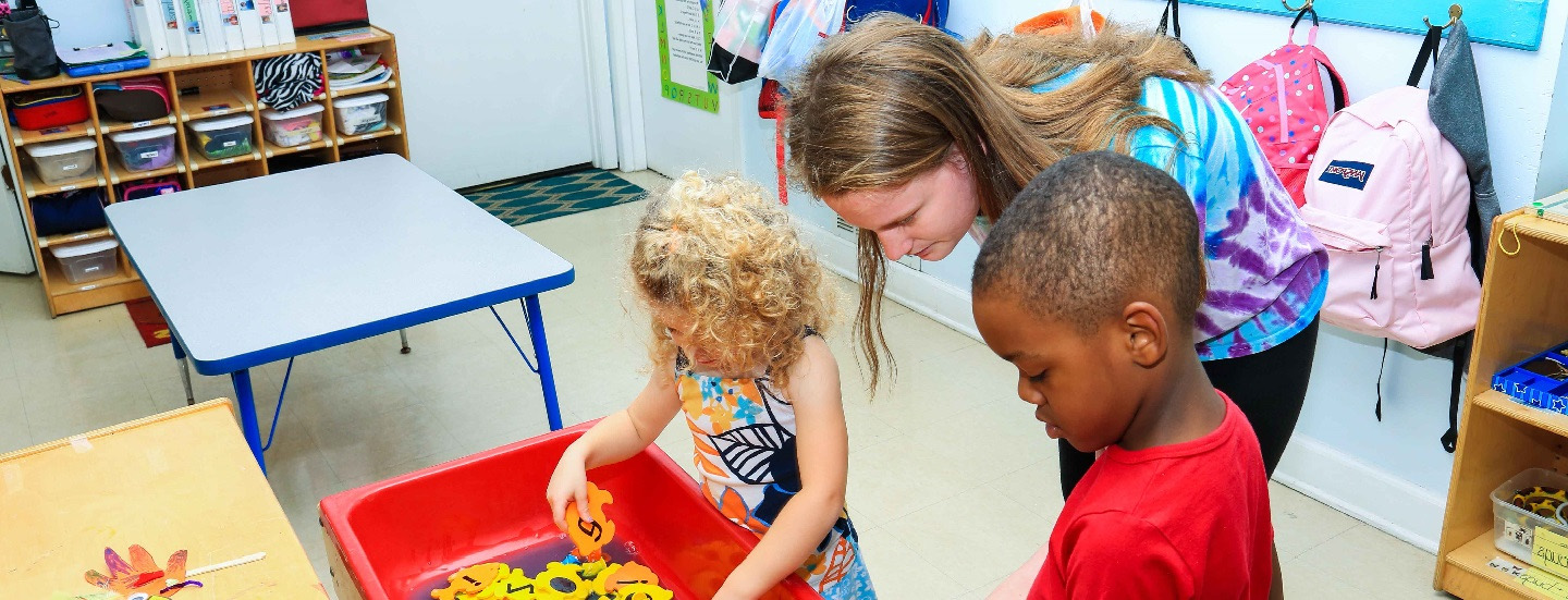 Children exploring the sensory water table with their teacher